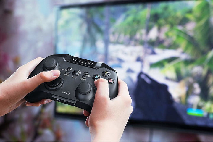 Hands hold a controller while playing a game on TV.
