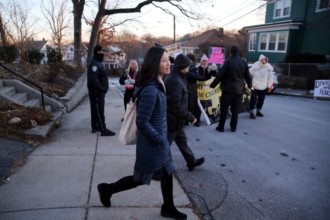 Boston Mayor Michelle Wu passes a small group of demonstrators as she leaves her home in the Roslindale neighborhood of Boston, on Jan. 26, 2022.