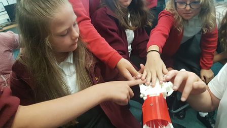 Causton Juniors students working with a 3D printed robotic hand.