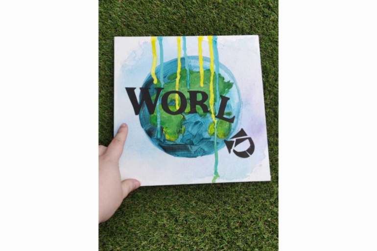 A photo of a sign that says the word "world" with a leaning L and D on an illustration of planet earth.