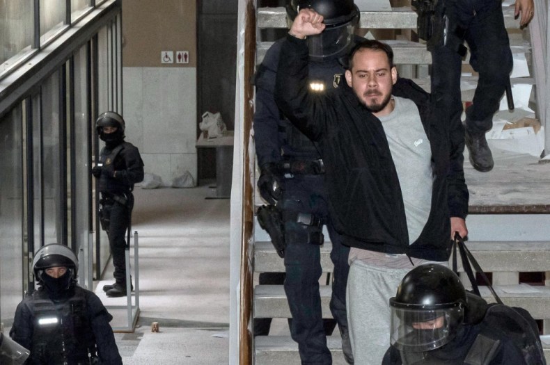 TOPSHOT - Catalan rapper Pablo Hasel is arrested by police at the University of Lleida, 150 kms (90 miles) west of Barcelona, on February 16, 2021 where he had barricaded himself. - Spanish police today arrested a rapper who barricaded himself inside a university after he was controversially sentenced to nine months in jail over a string of tweets, television images showed. Pablo Hasel had been given until the night of February 12 to turn himself in to begin serving his sentence after being convicted for glorifying terrorism, slander and libel against the crown and state institutions. (Photo by J. Martin / AFP) (Photo by J. MARTIN/AFP via Getty Images)