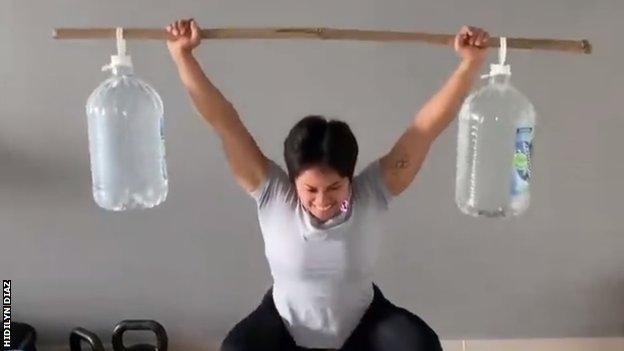 Hidilyn Diaz lifting makeshift weights made from bamboo sticks and water bottles.