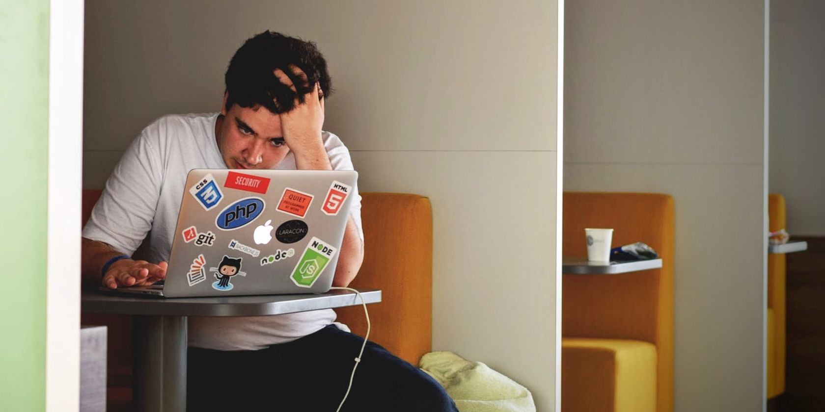 Stressed man using MacBook holding his head