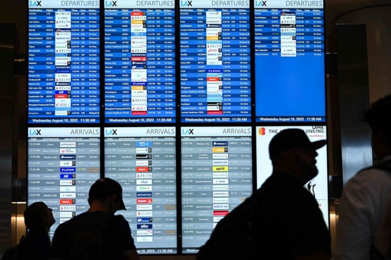 PHOTO: In this file photo taken on Aug. 10, 2022, passengers look at flight departure information boards in the West Gates expansion area at Los Angeles International Airport in Los Angeles.