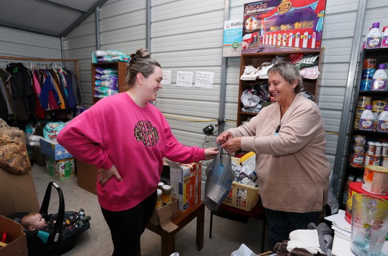 Donna Roark, right, gives a bag of formula to Nikki Hall for her son Noah Hall, 5 months, on Dec. 12, 2022 at The People's Building in Littcarr, Ky.  Roark has been seeking donations to distribute to victims of this year's flooding in eastern Kentucky.  She says that she has been providing essential items to people who are still recovering after losing property and belongings in the aftermath of the flood.