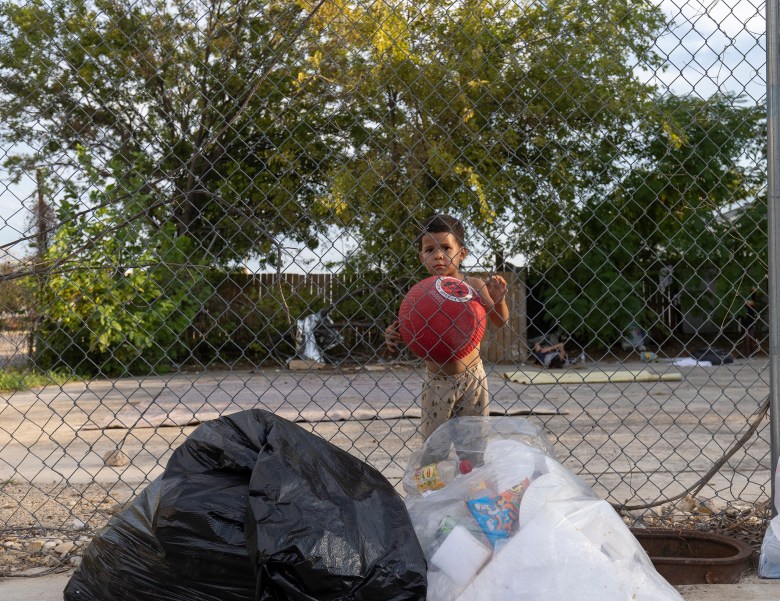 Sebastián Hidalgo, 3 holds a ball near bags of trash at a makeshift outdoor migrant shelter in the Shearer Hills/ Ridgeview area in September. Hidalgo immigrated with his mother from Venezuela.