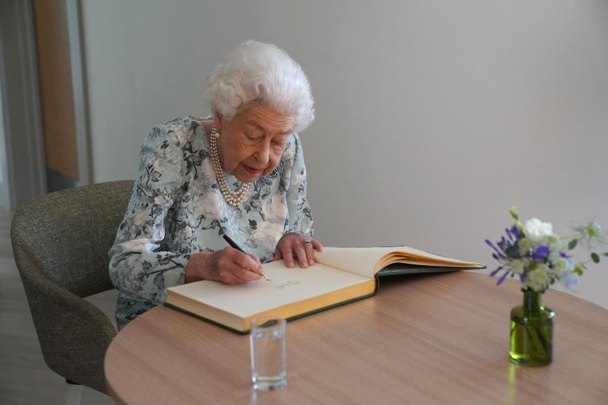 Britain's Queen Elizabeth II signs a guestbook during a visit to officially open the new building of Thames Hospice in Maidenhead, Berkshire, on July 15, 2022.