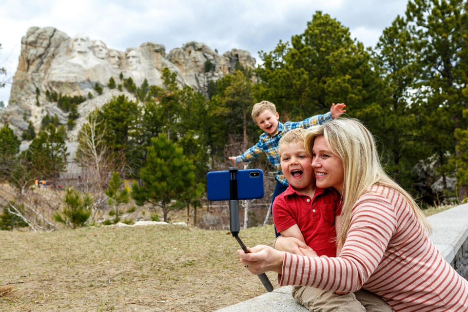A mother poses for a selfie with her two sons with Mt. Rushmore in the background