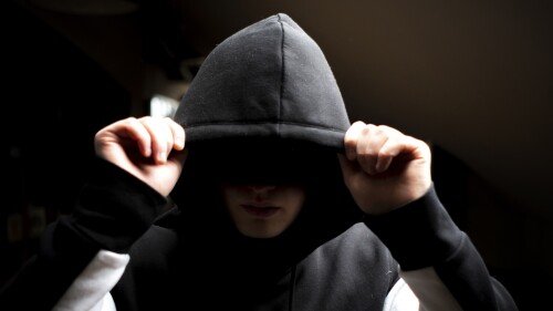 anonymous man in the dark hood standing in the mysterious pose f