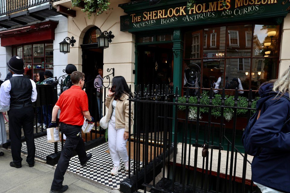 A delivery person carrying parcels outside the Sherlock Holmes Museum in London.