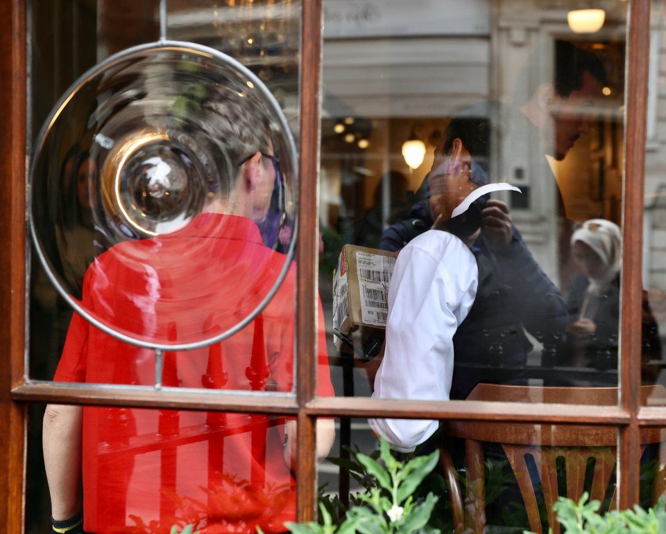 A postal worker handing two parcels to a museum manager, who is inspecting the labels.