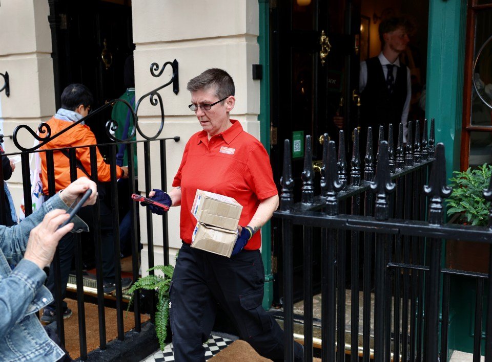 A postal worker carrying two packages outside the Sherlock Holmes Museum.