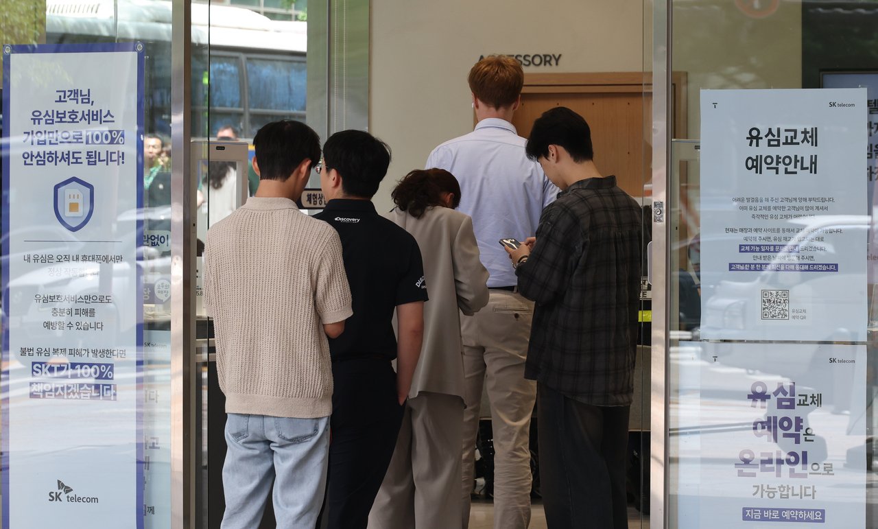 People wait in line to change their universal subscriber identity module chips at an SK Telecom Co. store in Seoul on Thursday. (Yonhap)