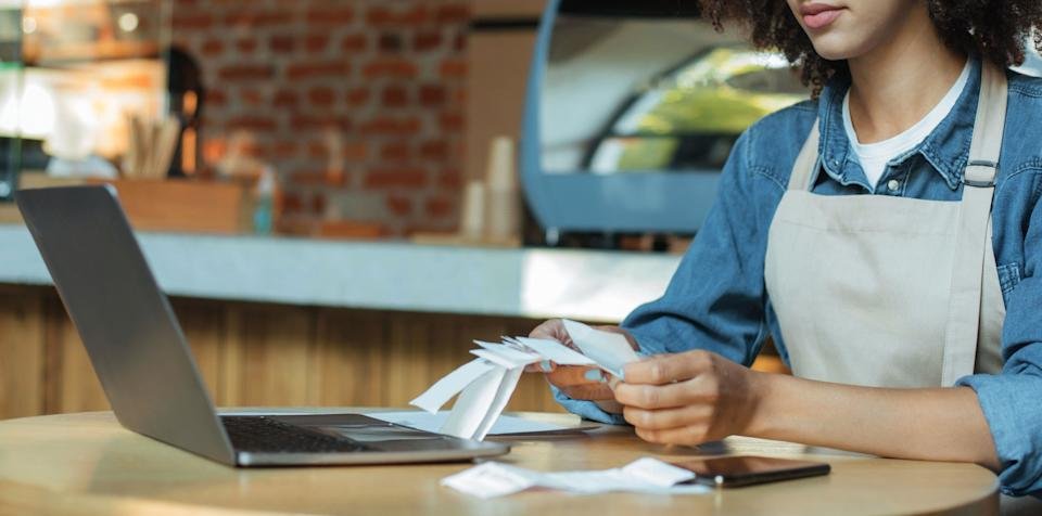 Millennial african american woman owner manager in apron works with account and bookkeeping in cafe, panorama, cropped