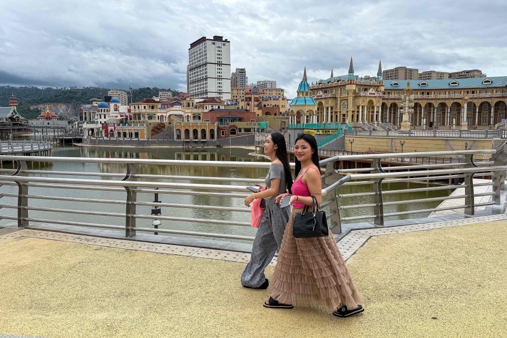 Women walk past the Little Venice and Diamond Plaza tourist attractions inside the Golden Triangle Special Economic Zone along the Mekong River in Bokeo province, Laos. — AFP pic