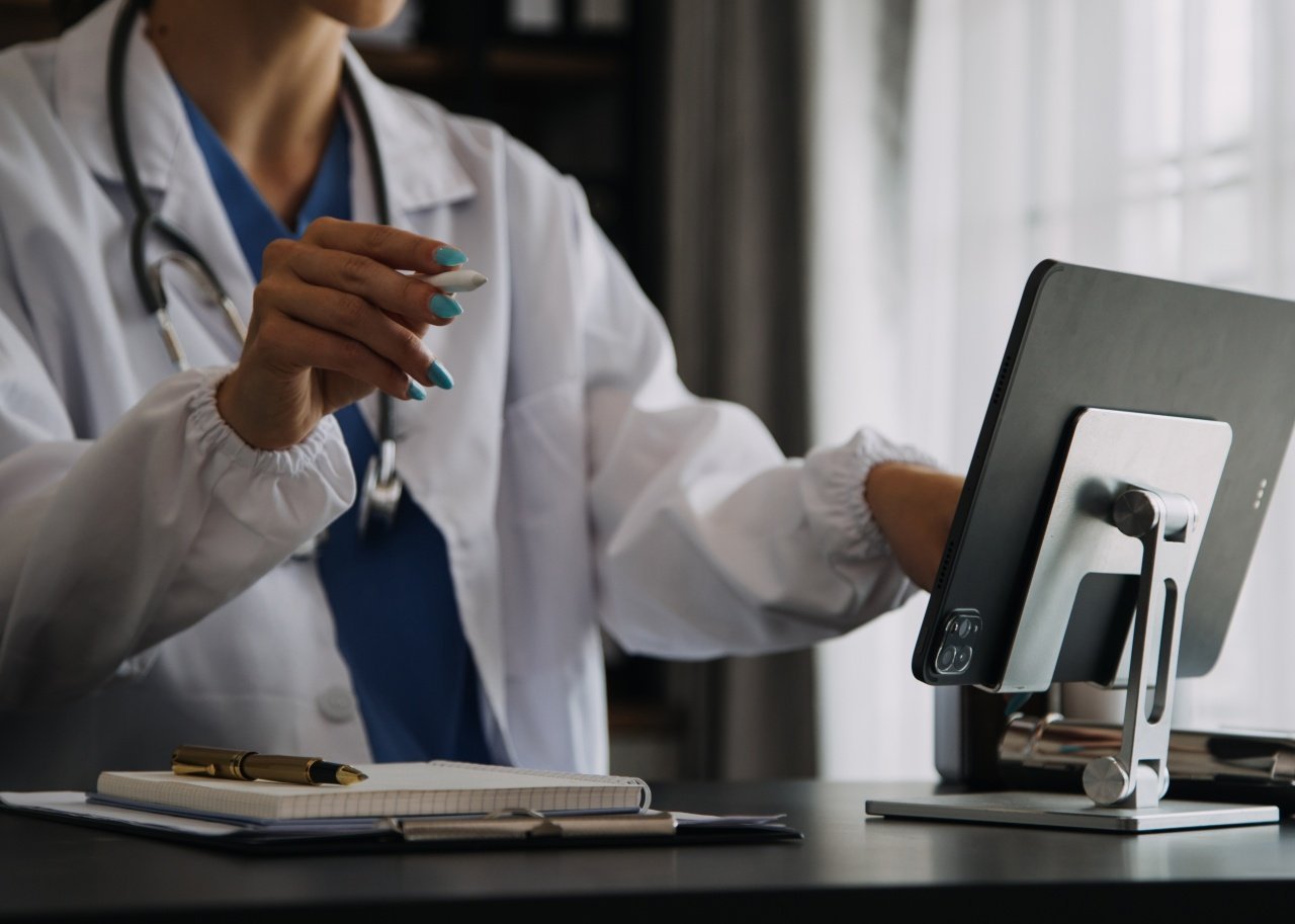 Young physician in white coat working on computer.