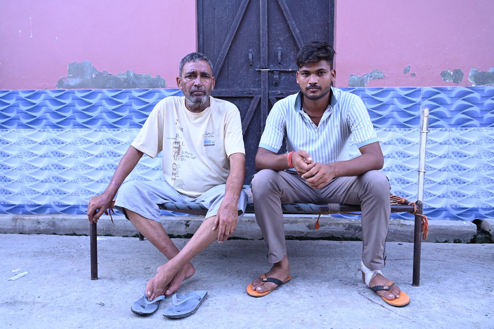 Tej Pal, a farmer and rickshaw driver, and his son sit outside their home after receiving a video call from people claiming to be police officers who demanded money to release his son from prison.