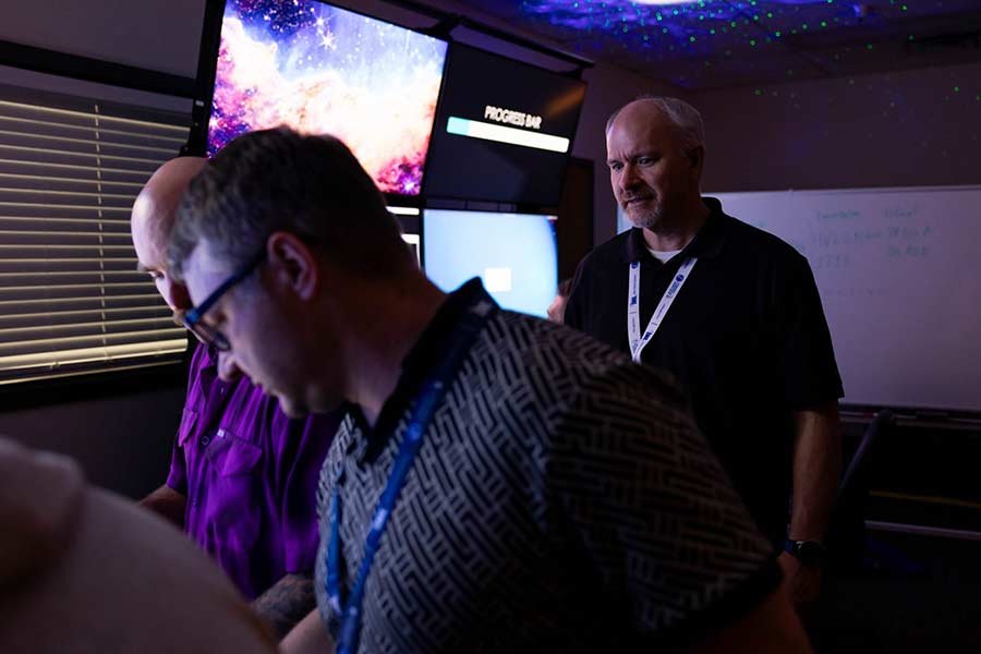 ICS 301 trainer Eric Mickelsen oversees two participants in one of the cyber escape rooms that are part of the program. | Courtesy INL