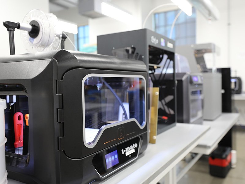 black 3d printers in a row inside an advanced manufacturing lab.