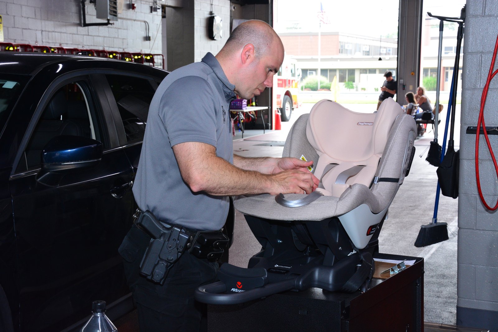 A New York State Trooper inspects a car to ensure its child safety seat is installed correctly during an event hosted by state Sen. Martinez on July 26, 2025.