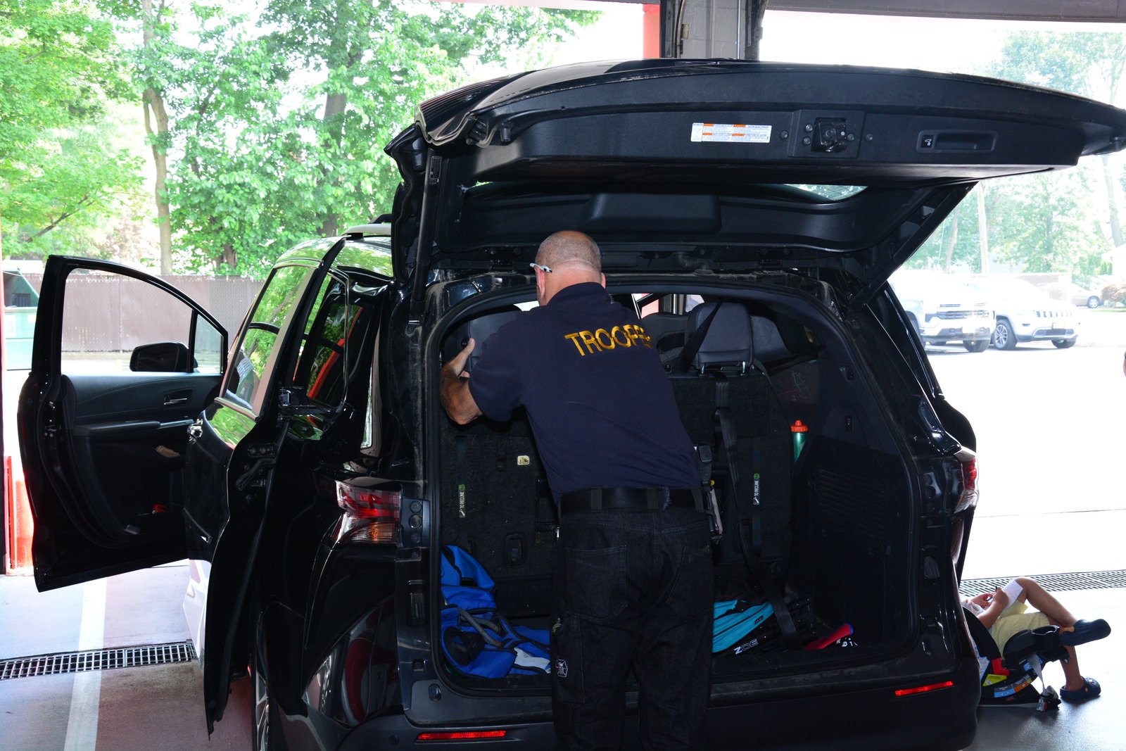A New York State Trooper inspects a car to ensure its child safety seat is installed correctly during an event hosted by state Sen. Martinez on July 26, 2025.