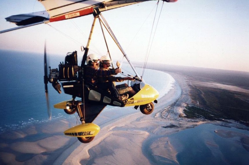 A light aircraft in the air above a coastline.