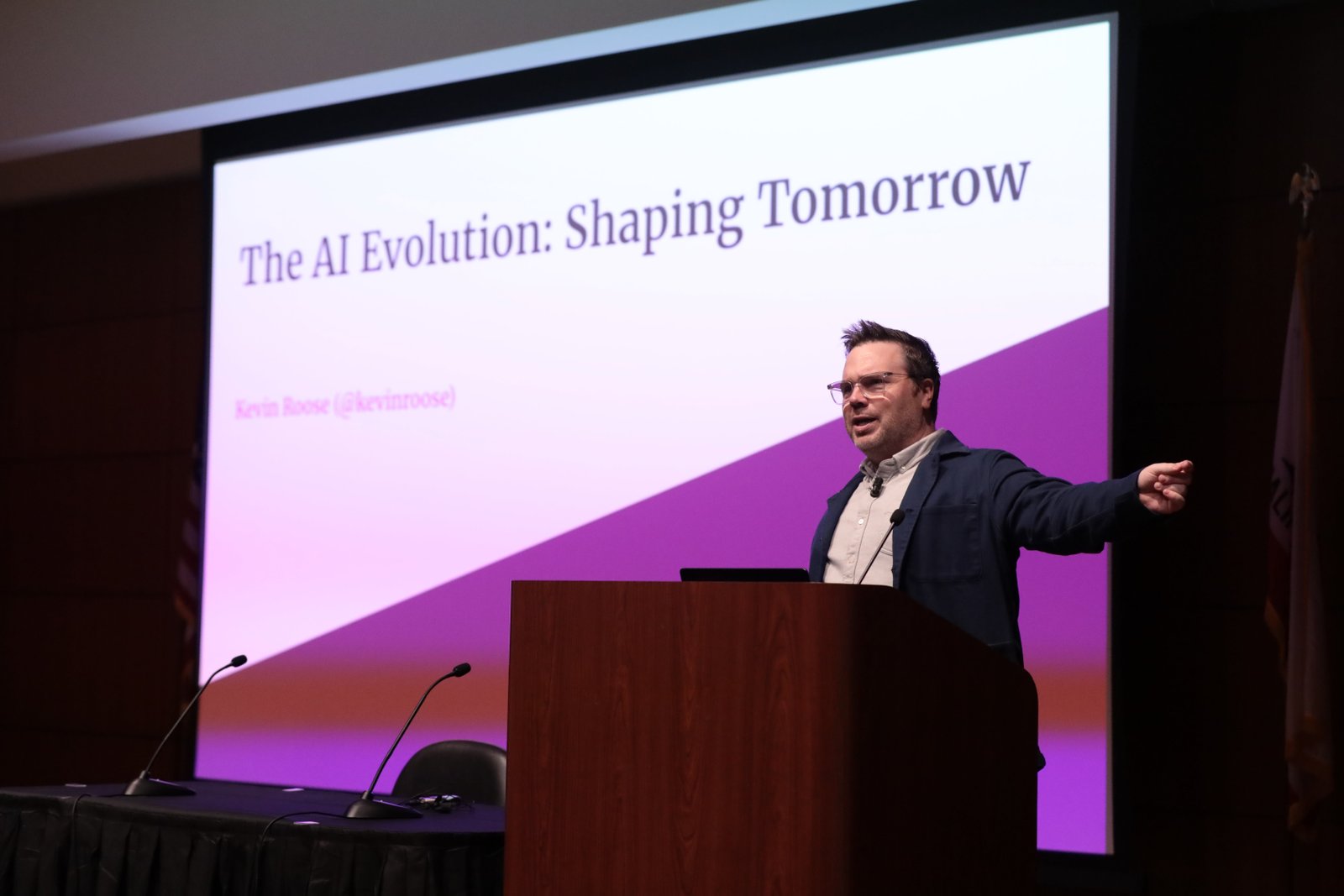 Kevin Roose stands at podium in front of projection screen.