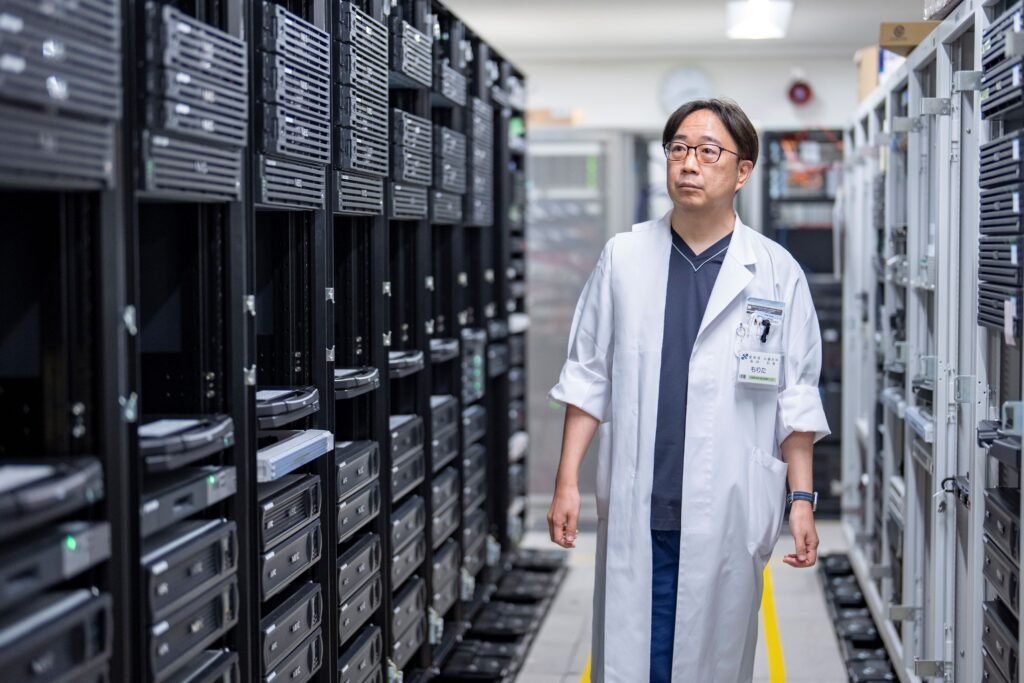 A man standing next to stacks of computer servers.