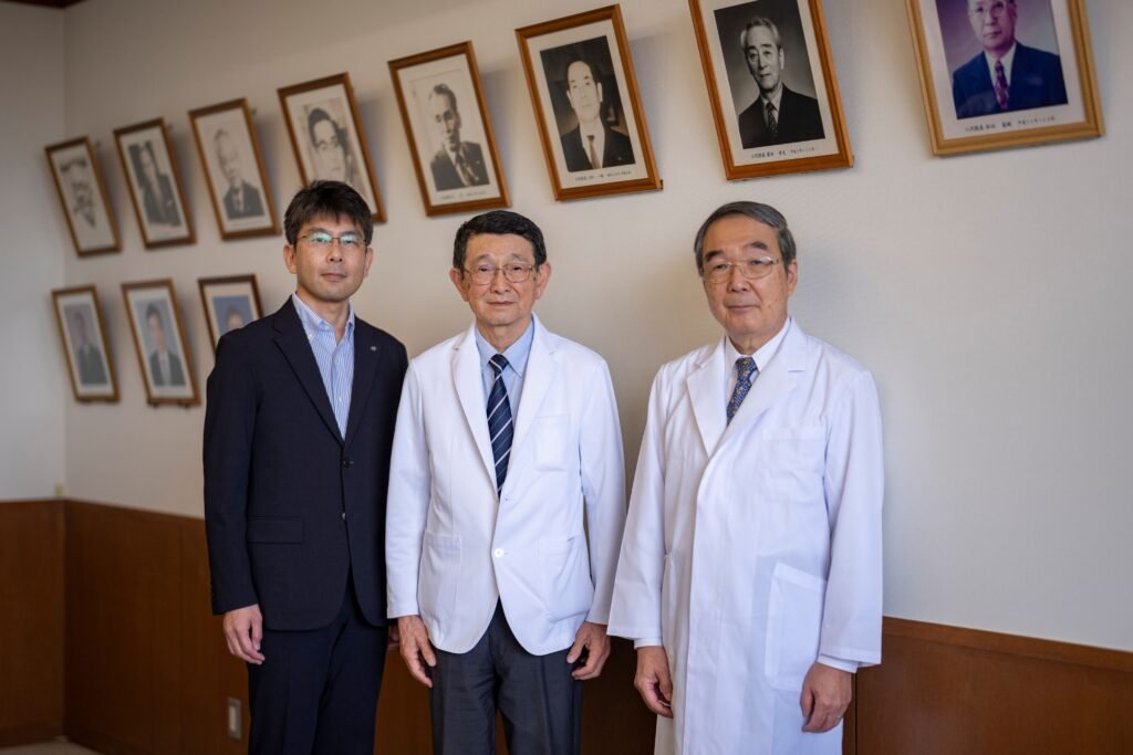 Three men standing in front of a wall of photos.