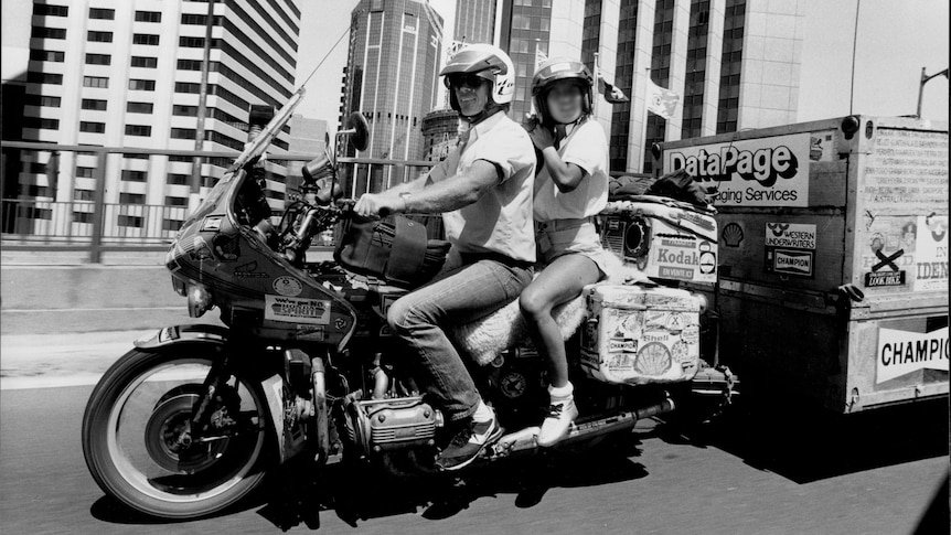 Black and white photo of a man and a woman on the back of a motorcycle